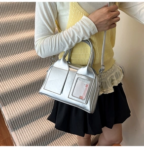 Silver metallic handbag with transparent card slot shown on stairs being carried by model