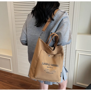 Detail of caramel canvas tote bag with adjustable shoulder strap worn cross-body