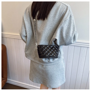 Detail shot of black quilted chain bag with silver ball adjustment buckle on model