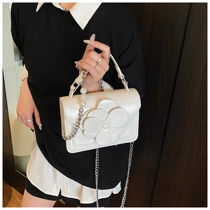 Detailed view of the 3D flower and pearl embellishment on the cream crossbody bag