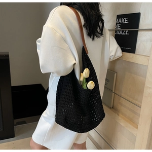 Detail of black hollow woven tote bag with brown leather handles and tulip decoration