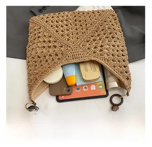 Detail of hand-woven straw tote showing wood bead handle and spacious inner compartment