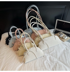 Glossy baguette bags in multiple sizes and colors arranged on a white bed with accessories