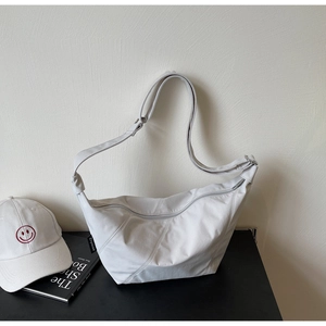 Detailansicht der cremefarbenen Tasche mit vertikalen Nähten und breitem Schultergurt