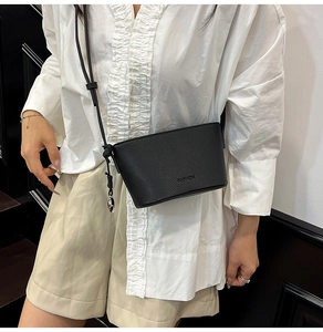 Detail einer schwarzen Bucket Bag aus Leder mit FASHION Logo und Metallschnalle
