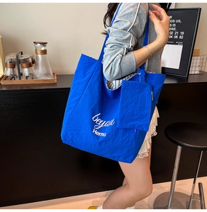 Detail of royal blue canvas tote bag with side pouch and beyou Hemu art lettering