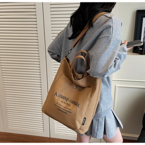 Detail view of brown canvas tote bag with adjustable shoulder strap and large outer pocket