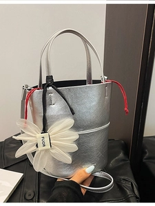 Silver metallic bucket bag with red drawstring and large white floral charm
