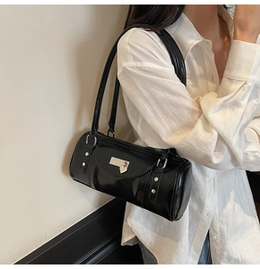 Detail of black glossy bowling bag with silver studs and heart charm on linen shirt