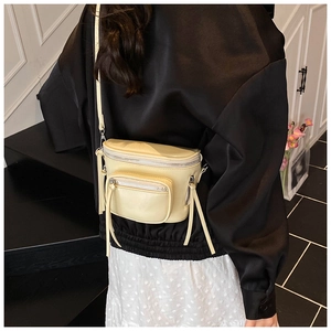Détail du sac bandoulière crème avec poches zippées et longues franges en cuir