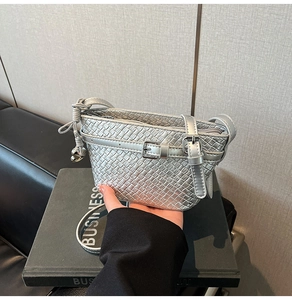 Dettaglio della borsa a tracolla intrecciata argento con ciondolo M e cinturini con fibbia