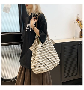 Close-up of contrast striped knit tote with leather strap and white flower charm