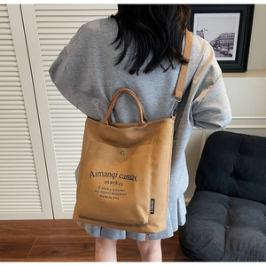 Detail showing brown canvas tote bag with large front pocket and long shoulder strap