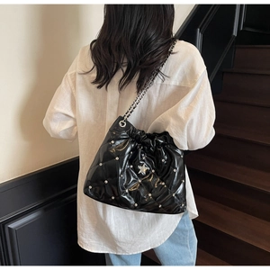 Détail du sac seau en cuir matelassé avec clous en étoile et bandoulière chaîne
