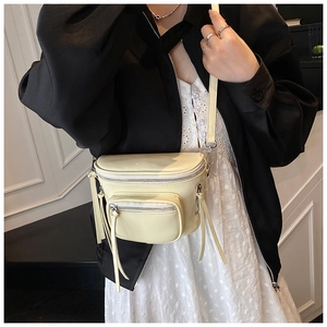 Détail du sac seau demi-lune crème avec double fermeture éclair et pompons en cuir