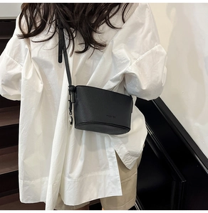 Detail der schwarzen Beuteltasche aus genarbtem Leder mit Anhänger und Fashion-Logo