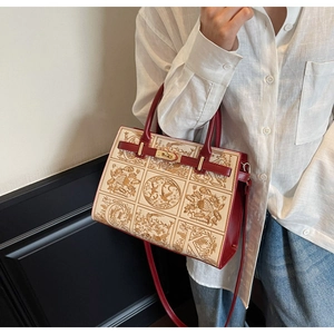 Detail of red and beige embroidered handbag with gold floral patterns and metal lock
