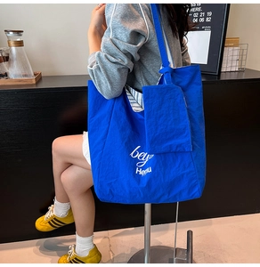 Detail of blue tote bag with white lettering and striped lining for student commute