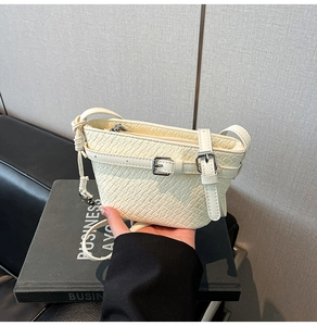 Dettaglio della borsa a tracolla bianco sporco con cinturini decorativi e fibbie argento