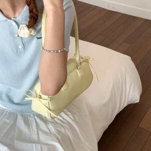 Close-up of a pale yellow bow baguette bag with smooth texture and zipper detail