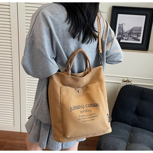 Detailed view of khaki canvas tote bag with adjustable strap shown in a lifestyle setting