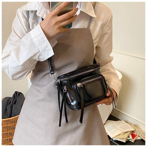 Détail du sac bandoulière noir brillant avec fermetures éclair argentées et poche