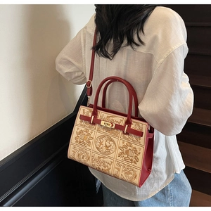 Detailed view of red and beige embroidered handbag worn by model on stairs