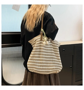 Detail of knitted tote bag with brown leather strap and decorative tulip pendant charm