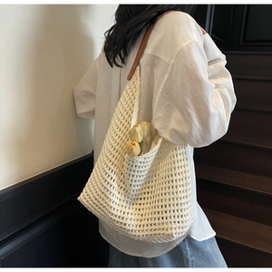 Detailed macro view of a white crochet hollow knit tote bag with a brown leather shoulder strap