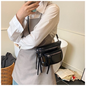 Détail du sac bandoulière noir brillant avec deux poches zippées et boucles argentées