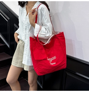 Detail of red canvas tote bag with white text print and striped inner lining detail