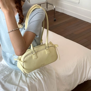 Detail of light yellow PU leather baguette bag with bow knots and zipper closure