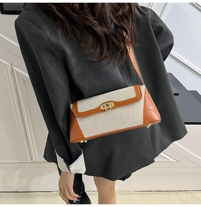 Detail of contrasting beige canvas and brown leather flap bag with gold twist lock