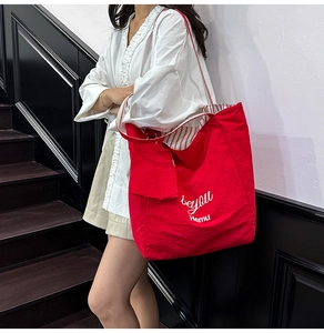 Detail of red tote bag featuring be you print and striped inner lining for casual use