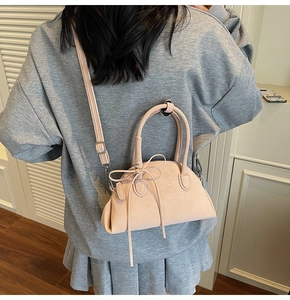 Detail of light pink shell shoulder bag with decorative bow and silver hardware