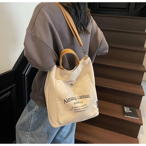 Detail of canvas tote bag showing thick texture, front pocket, and adjustable shoulder strap