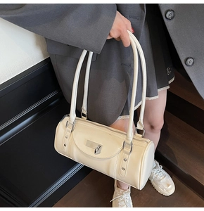Detailed side view of beige bowling bag featuring a heart pendant and silver metal hardware