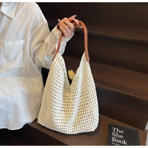 Detail of crochet knit tote bag featuring hollow texture and brown leather handle