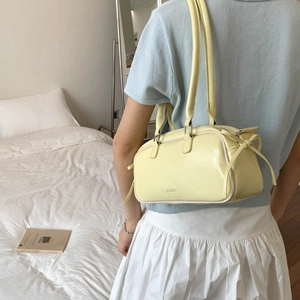 Chic yellow patent leather shoulder bag with drawstring detail shown in lifestyle setting