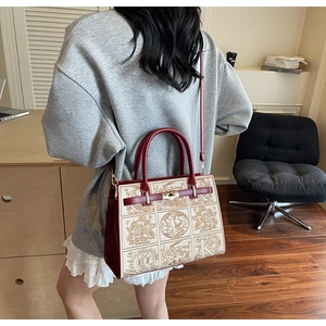 Detail view of the elegant embroidered floral tote bag with wine red leather trim accents