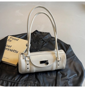 Detail of ivory bowling bag featuring a heart pendant and long handles on a leather jacket