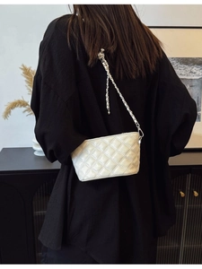 Chic beige quilted bucket bag with chain strap shown on model in stylish indoor setting