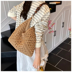 Detail of hand-woven straw tote with hollow floral patterns and wooden bead handle