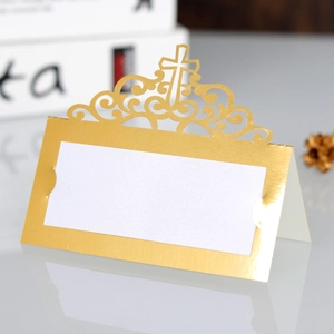 Detail of gold laser-cut cross wedding place card with elegant hollow pattern on white card