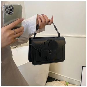 Detail of black crossbody bag with large 3D leather flower and curved handle