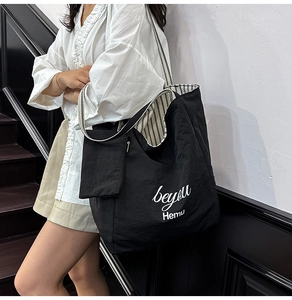 Detail of black tote bag with striped lining and removable small matching pouch