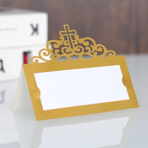 Close-up of golden laser-cut cross place card with elegant hollow pattern for wedding tables