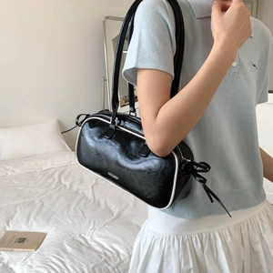 Detail of black faux leather bag with white piping and decorative side bows for women