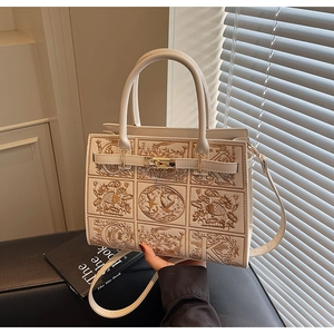 Detailed view of cream-white handbag featuring intricate floral embroidery and gold turn-lock