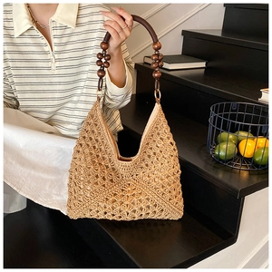 Detail of hand-woven straw tote bag with beaded handle and intricate floral patterns